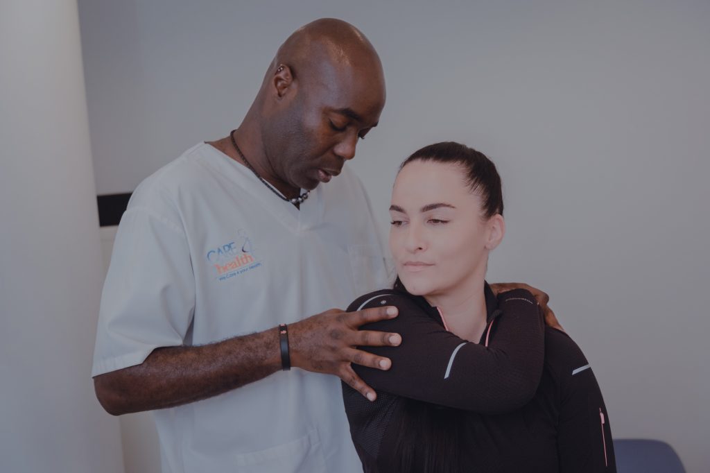 Physiotherapist guiding a female patient through a shoulder stretch during a manual therapy session